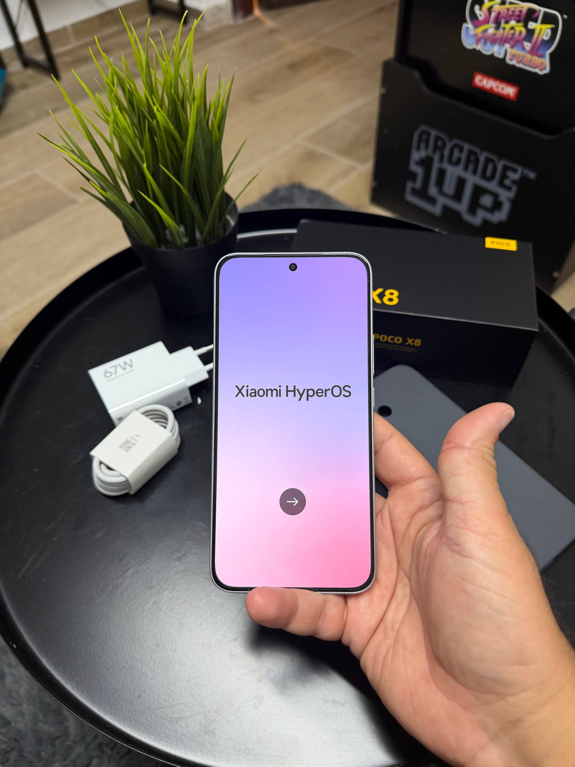 אחיזת POCO X8 5G עם מסך הגדרת HyperOS מעל ערכת האריזה